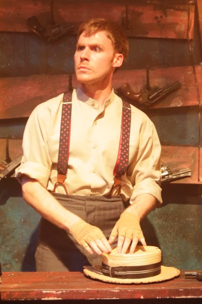 Jeff Meyer as the Proprietor of a shooting gallery on the weathered fairgrounds set designed by Zachary Gipson for Kokandy Productions at Theater Wit (Joshua Albanese)